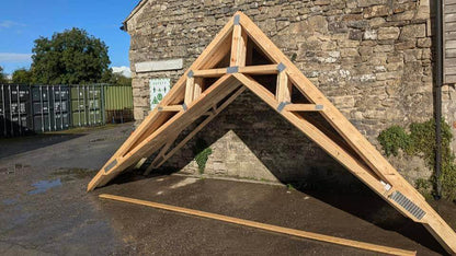 wooden scissor trusses stacked against a wall