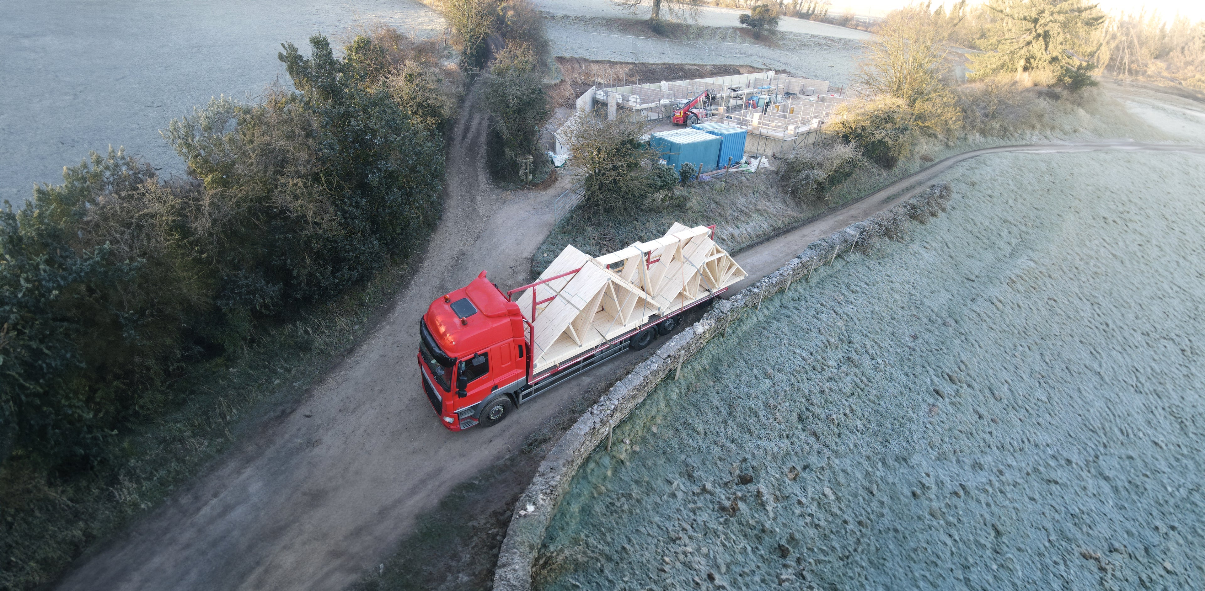 a lorry delivering roof trusses to a winter building site