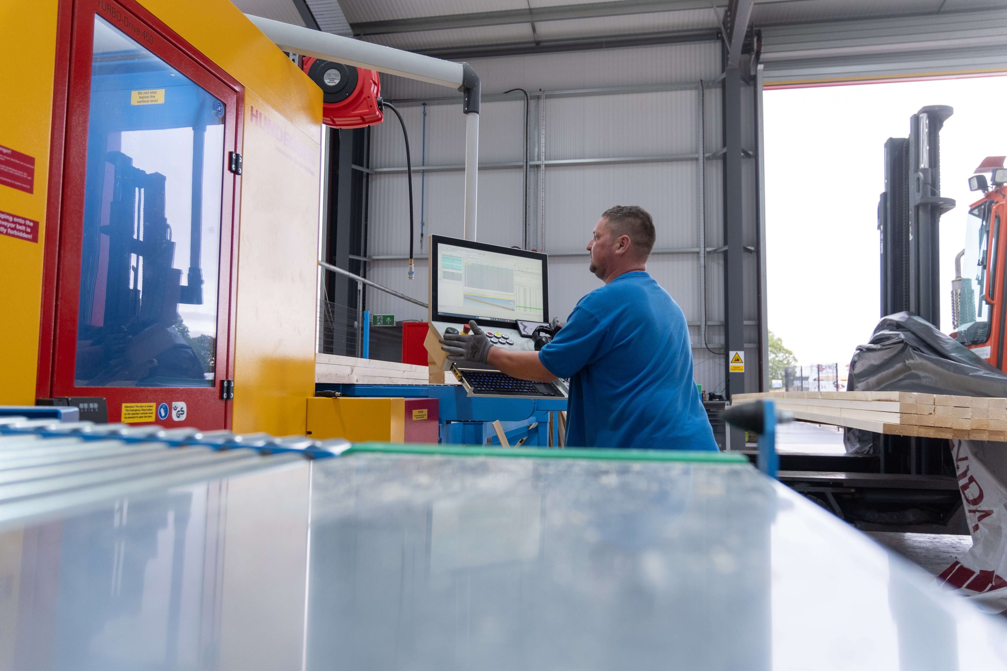 man in factory cutting timber using specialist equipment